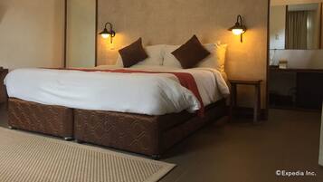 A hotel room with a large bed, two bedside lamps, a mirror, and a small table.