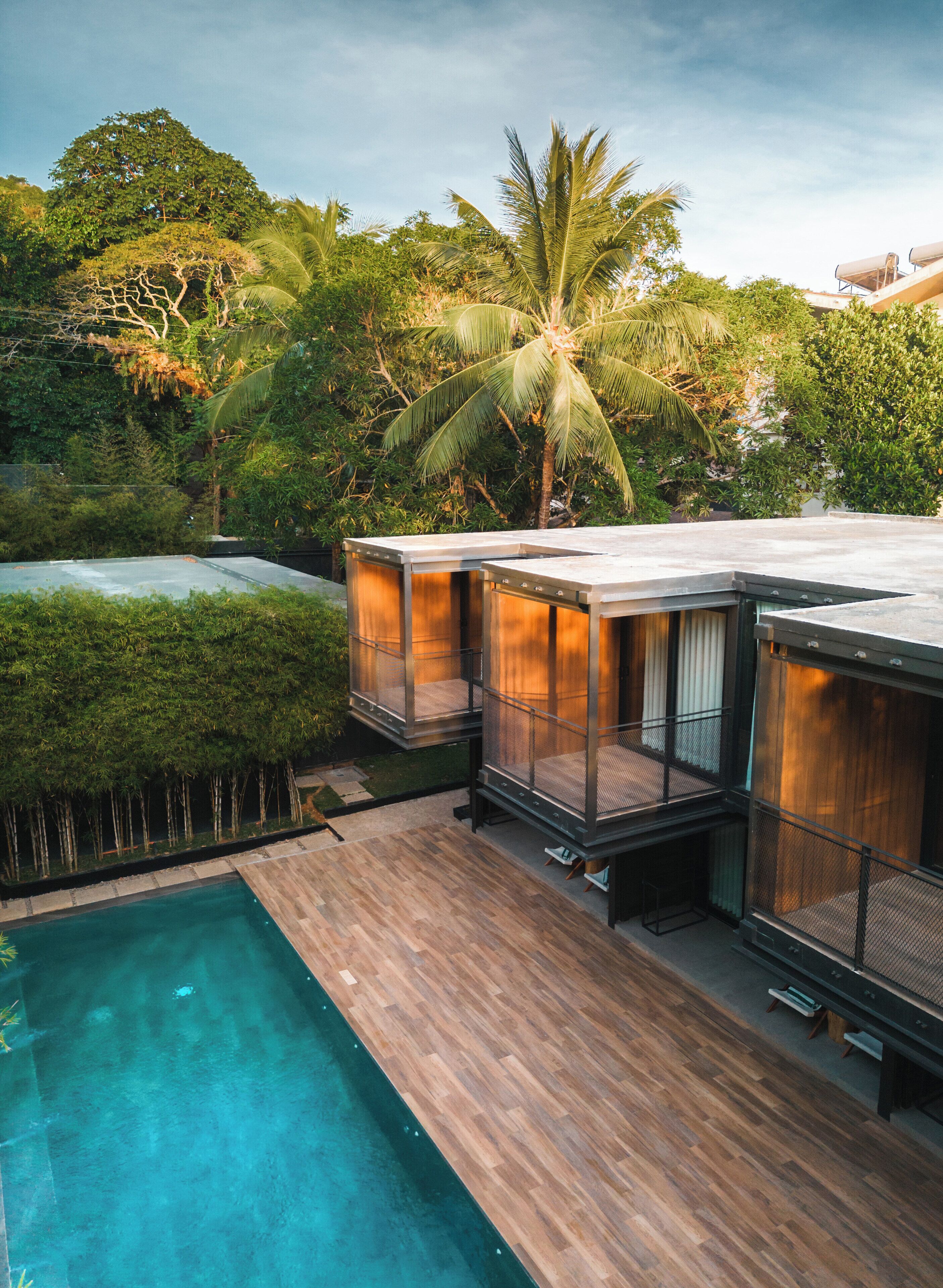 Eine moderne Villa mit Pool, Sitzgelegenheiten im Freien und üppiger Bepflanzung.
