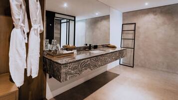 A modern bathroom with a large mirror, marble countertop, and a wooden cabinet.