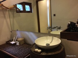 Une salle de bain avec un grand miroir, un lavabo blanc, un tonneau en bois et un porte-serviettes.