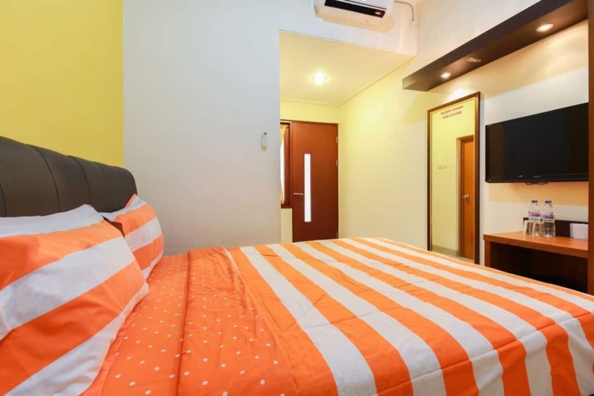 Une chambre d’hôtel avec un lit, une télévision et une porte donnant sur une autre pièce.
