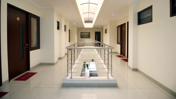 A hotel corridor with a central glass railing, doors on either side, and a ceiling light. - My Residence Cirebon (West Cirebon)