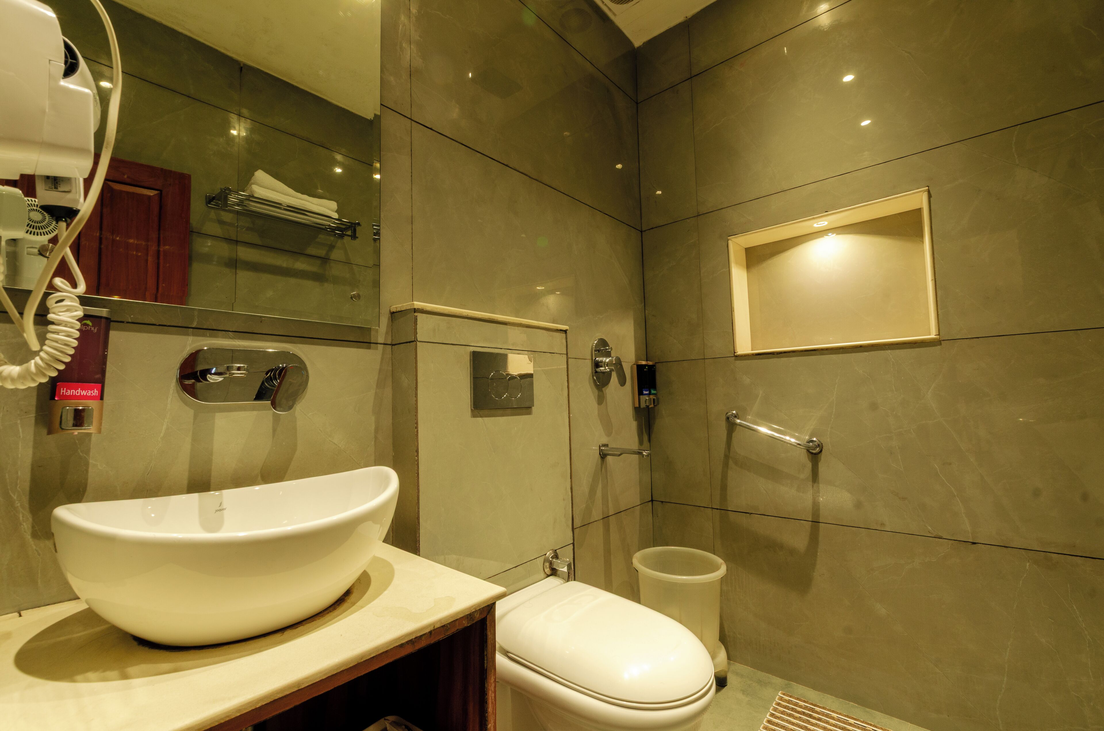 A bathroom with a large white sink, a toilet, a hand dryer, and a shower area.