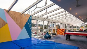 A covered outdoor area with a climbing net, a blue padded surface, and a pool table. - Kingston Hotel (Kingston)