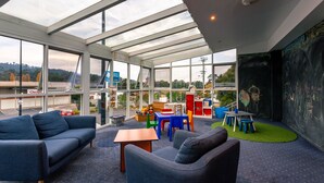 A modern interior with a glass ceiling, a children's play area, and a view of the outside. - Kingston Hotel (Kingston)
