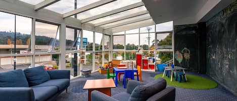 Un interior moderno con techo de vidrio, zona de juegos para niños y vistas al exterior.