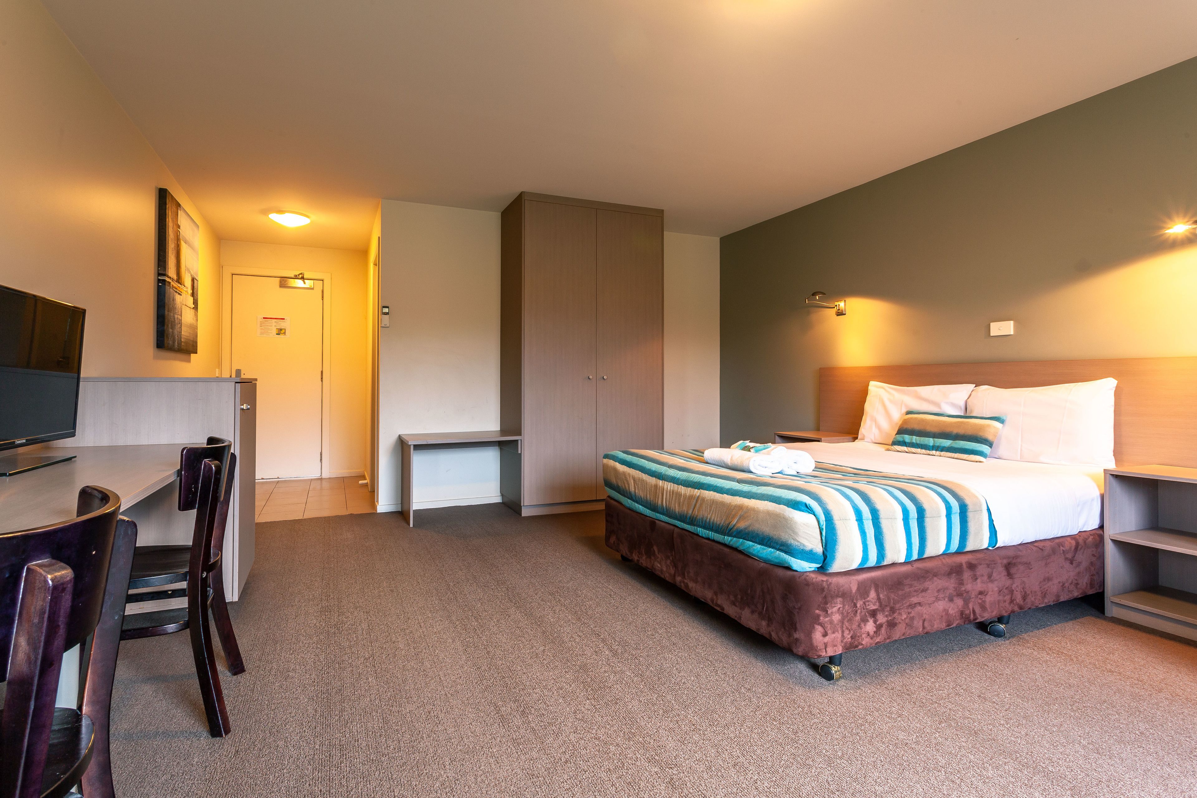 A hotel room with a bed, a desk, and a chair.