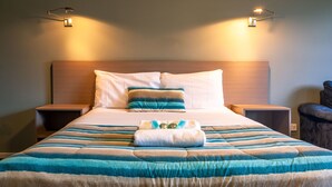 A neatly made bed with striped bedding, two bedside tables, and wall-mounted reading lights. - Kingston Hotel (Kingston)