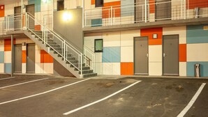A multi-story motel with a staircase leading to the upper floor, a parking lot, and a colorful exterior. - Kingston Hotel (Kingston)