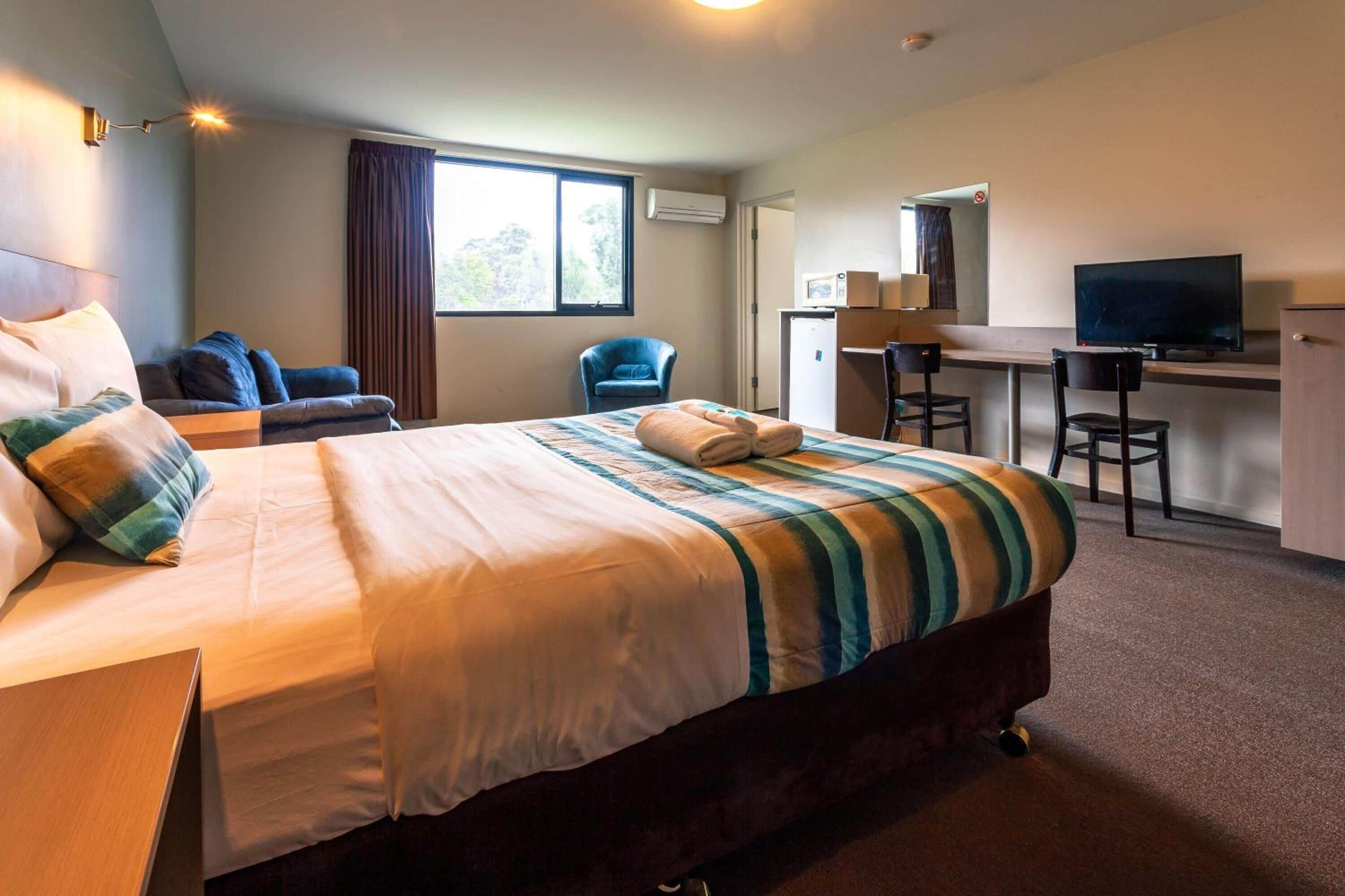 Una habitación de hotel con una cama grande, un escritorio, un televisor y una silla.
