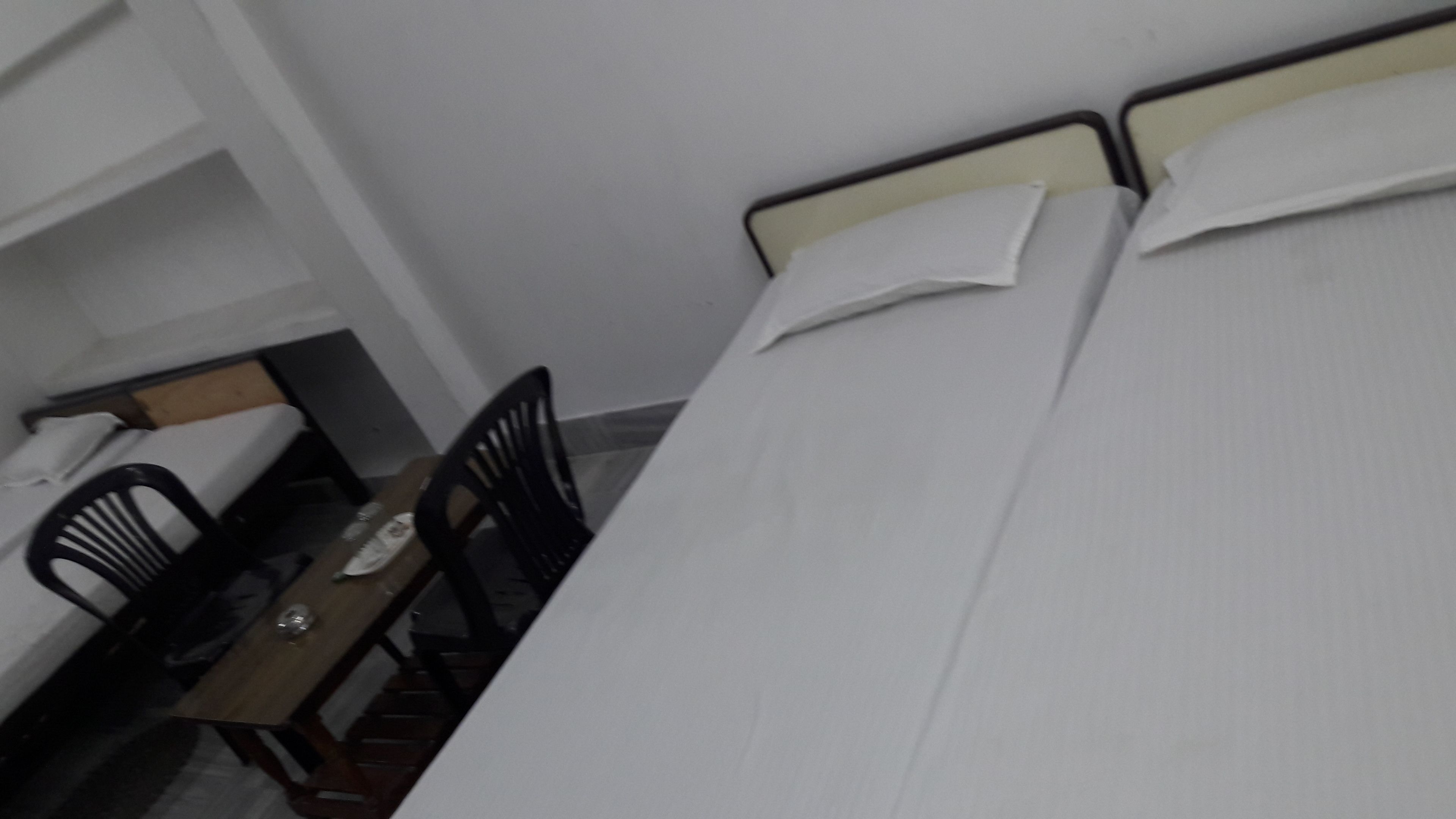 A small, single-bed room with a wooden table and two chairs.