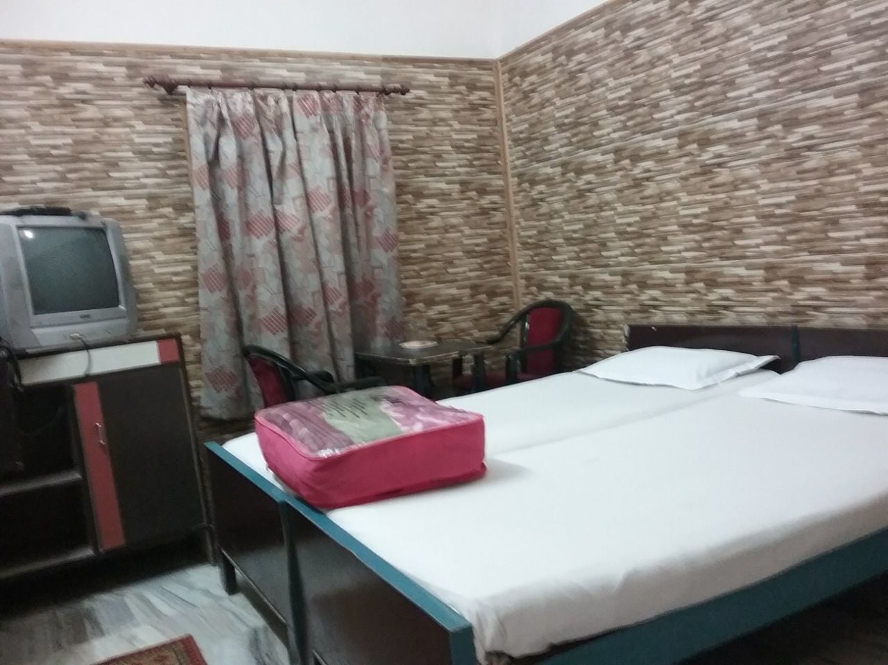 A room with a bed, a desk, a television, and a curtain.