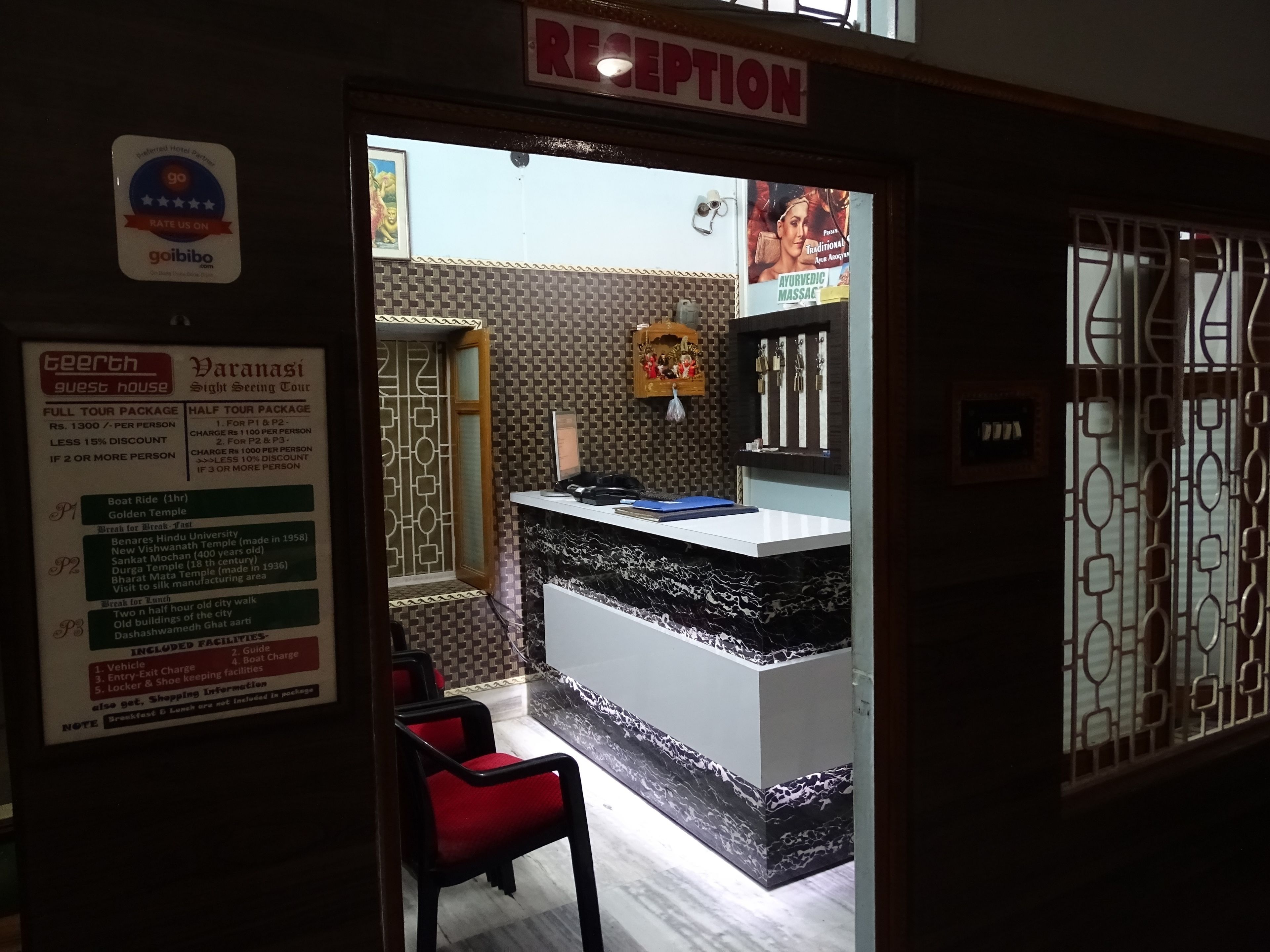 A reception area with a reception desk, a chair, and a wall with a signboard.