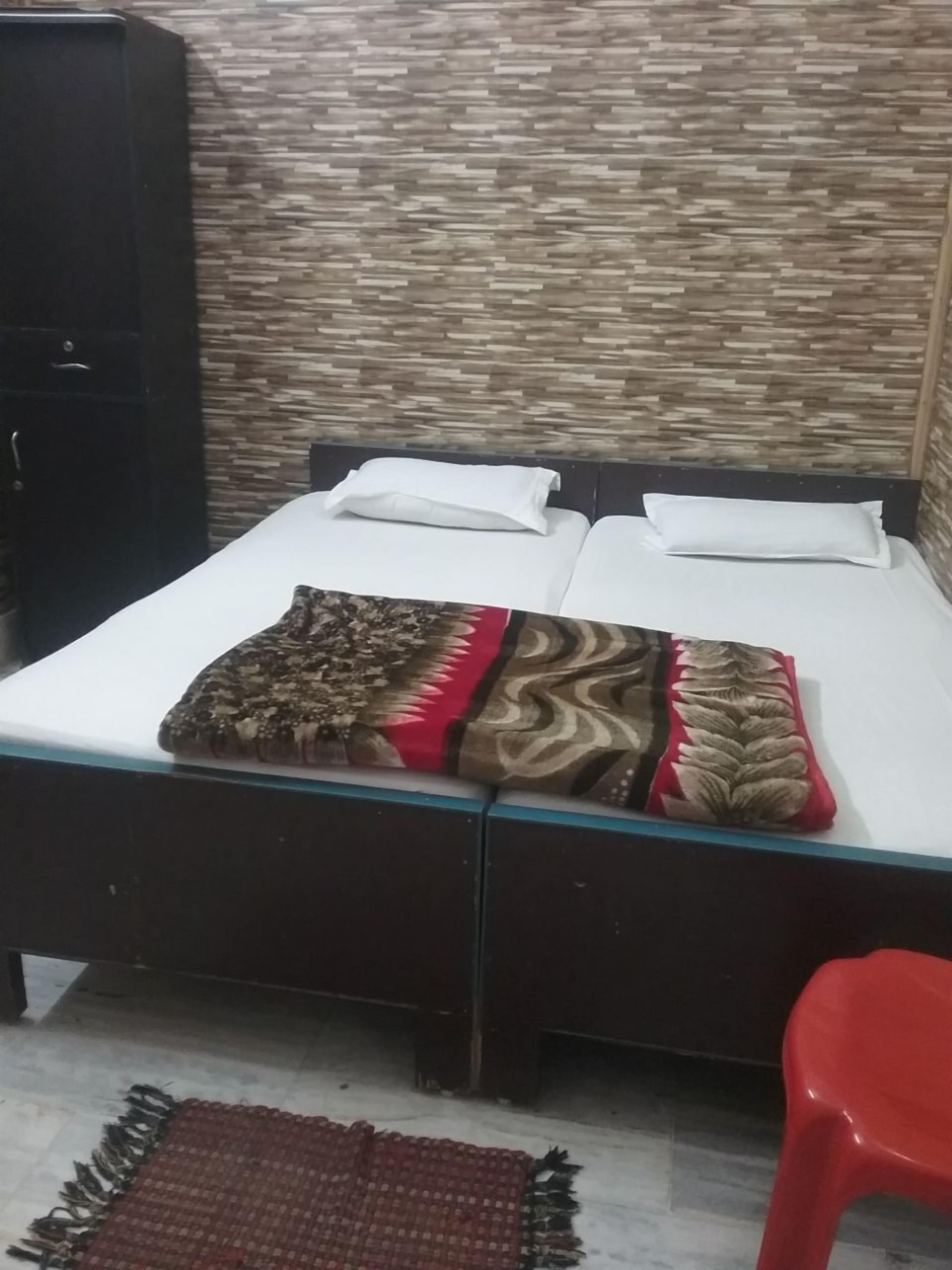 Ein Bett mit einem gemusterten Überwurf, weißen Kissen und einem dunklen Kopfteil.