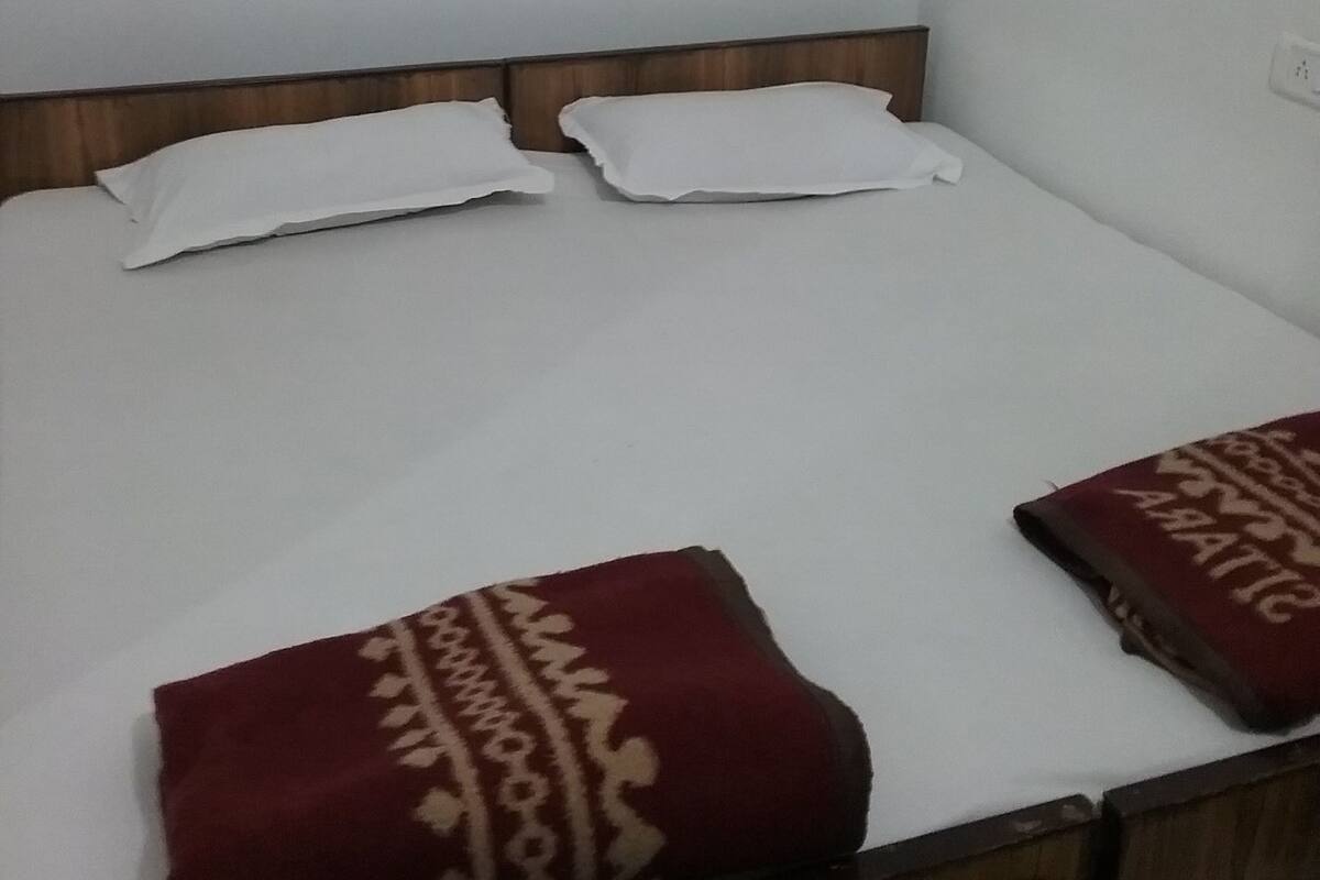 A single bed with a wooden headboard, white bedding, and two decorative pillows.