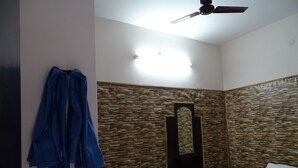 Un dormitorio con cama, una silla, ventilador de techo y pared con textura.