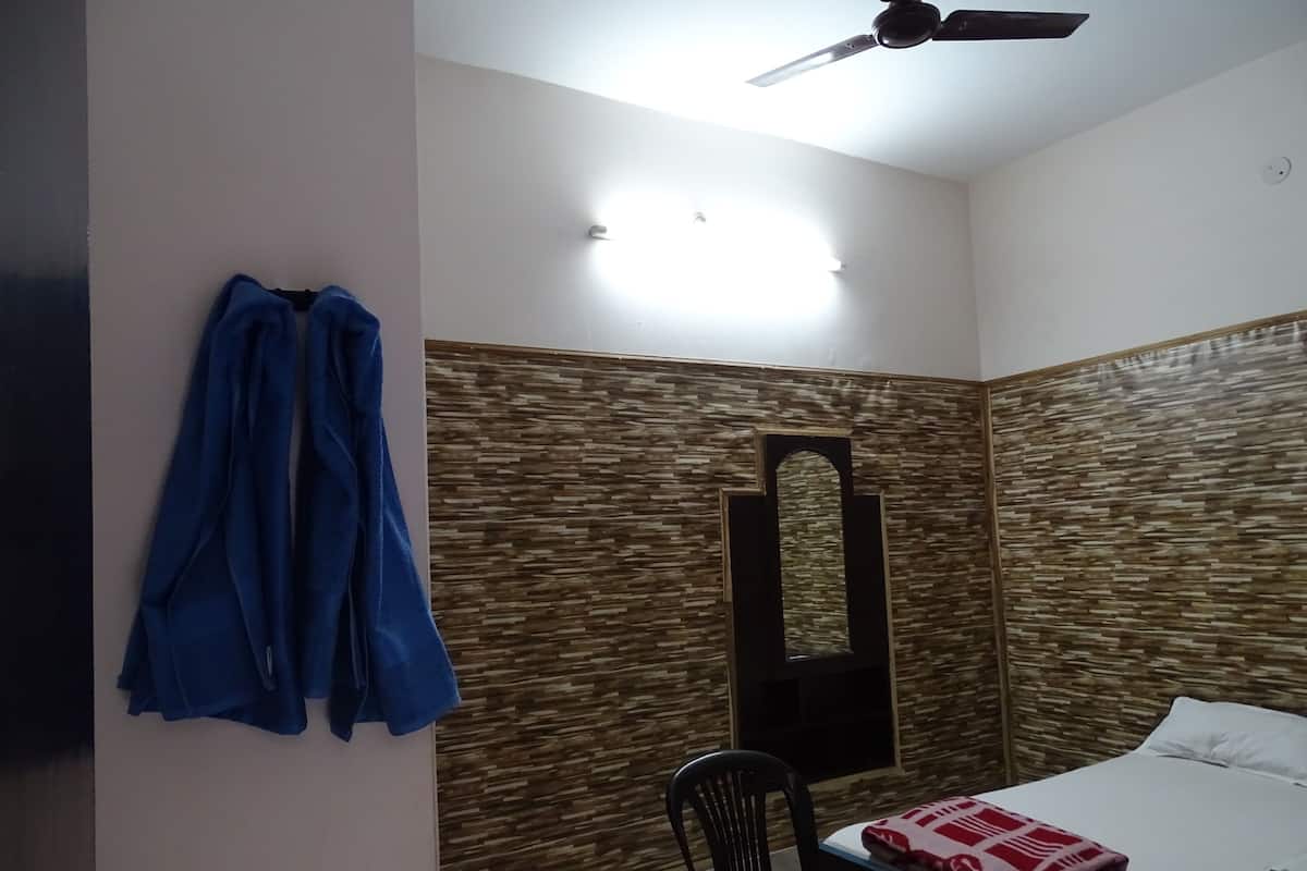 A bedroom with a bed, a chair, a ceiling fan, and a wall with a textured pattern.