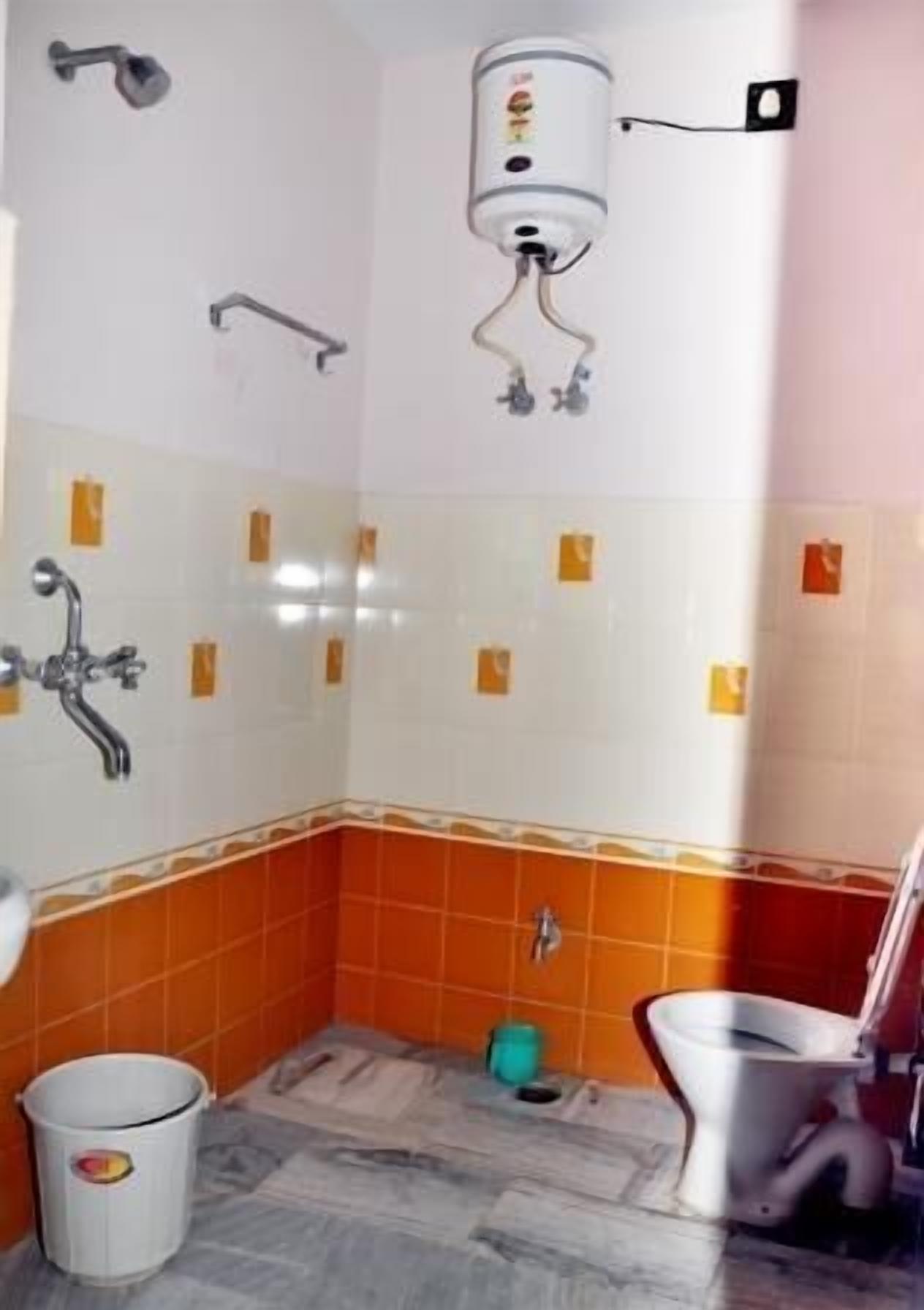 Et badeværelse med toilet, vask og brusebad.