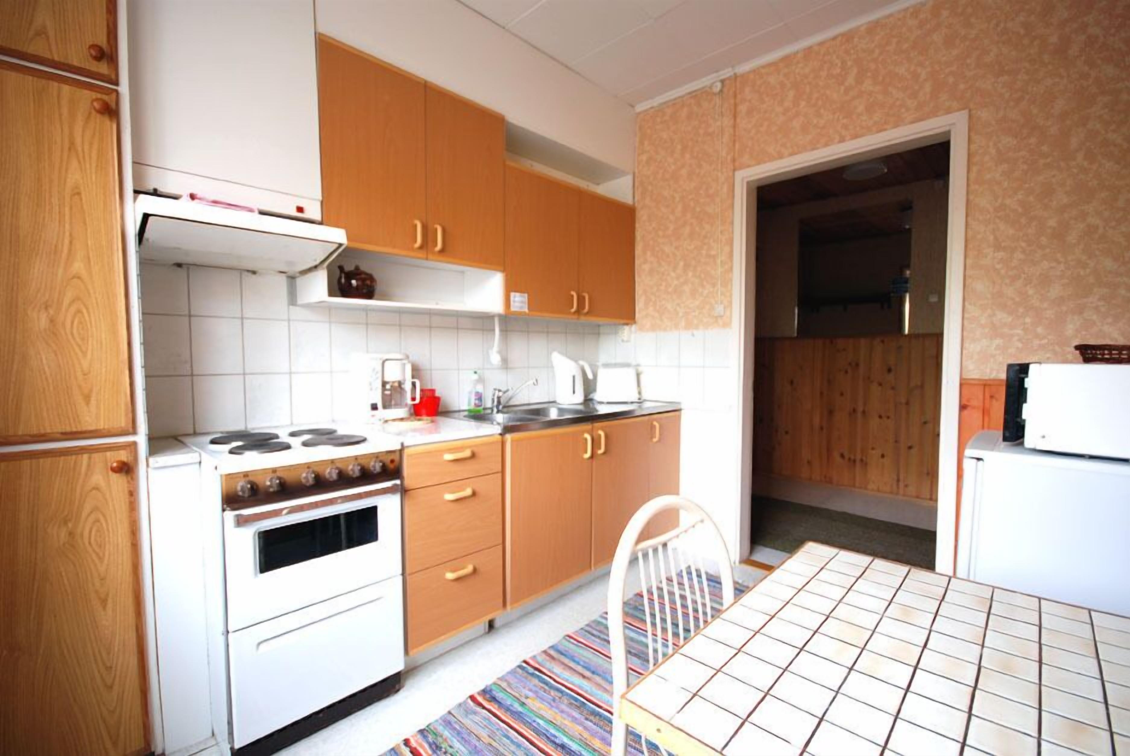 A compact kitchen with wooden cabinets, a white stove, and a tiled backsplash.
