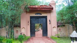 A building entrance with a tiled roof, a black door, and a sign above the door. - Tuli Tiger Resort (Bichhiya)