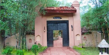 Una entrada de edificio con techo de tejas, puerta negra y un letrero encima.