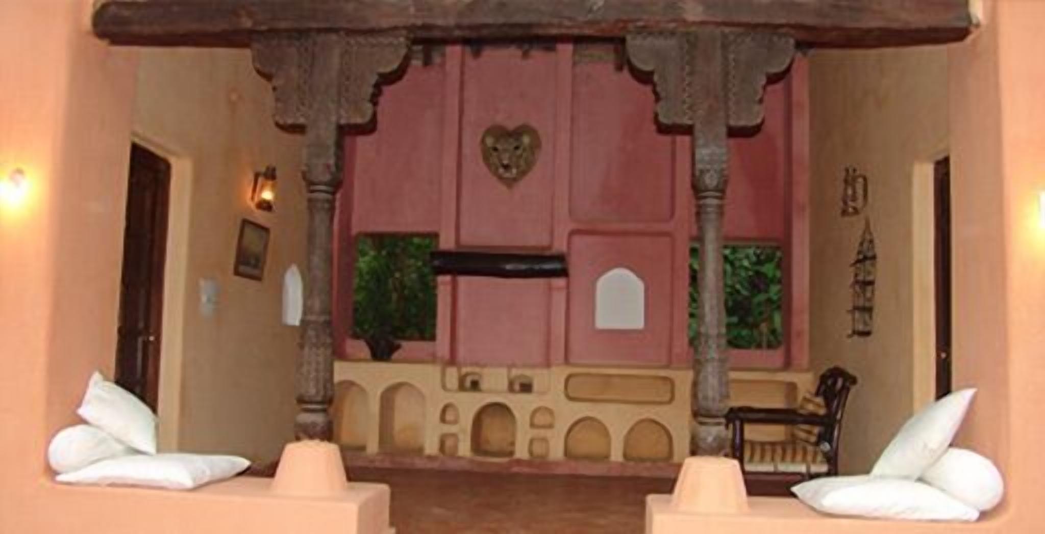 A room with a traditional design, featuring a central alcove with a heart-shaped decoration, a small table, and two white cushioned chairs.