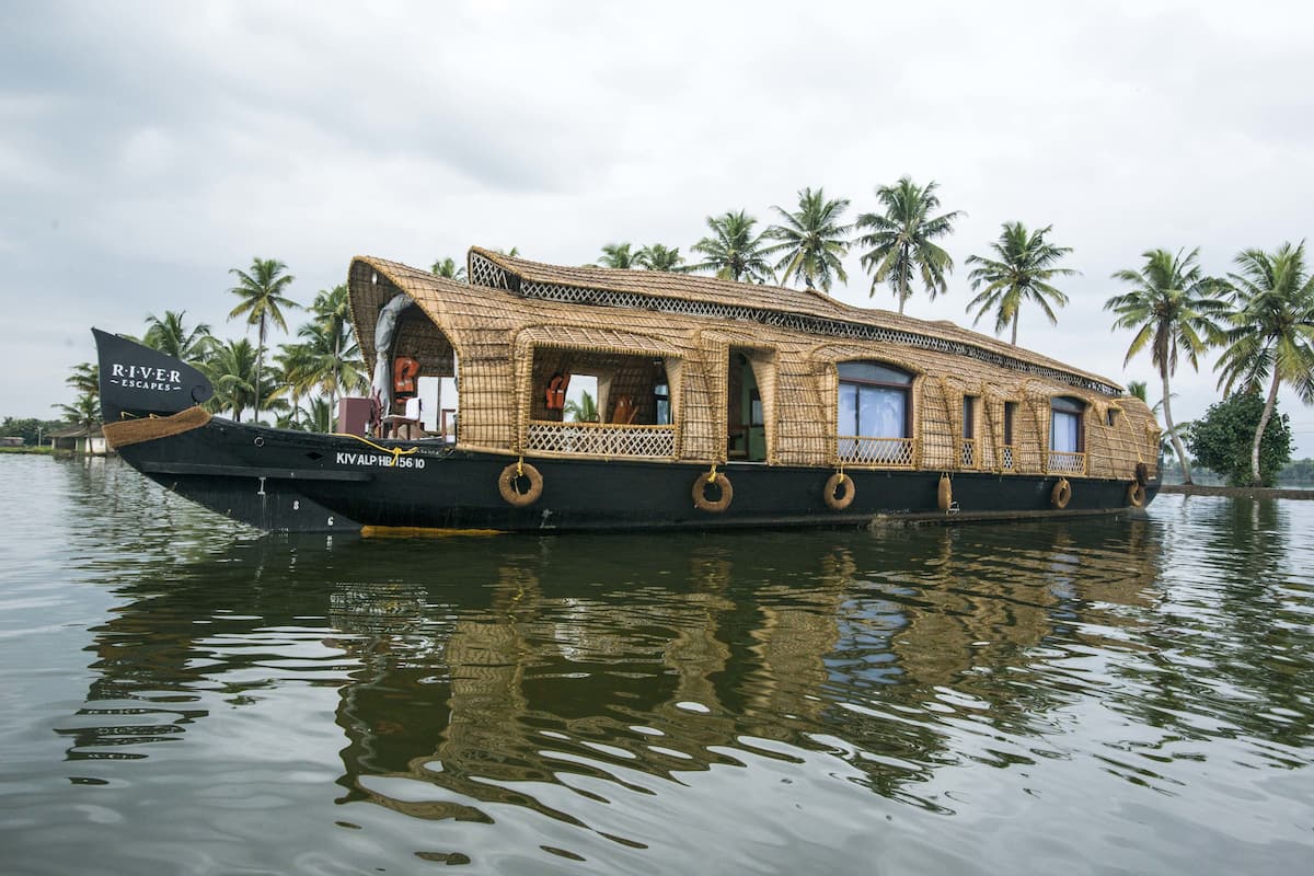 Una casa flotante con techo de paja, múltiples ventanas y el nombre 'River Escapes' en la lateral.