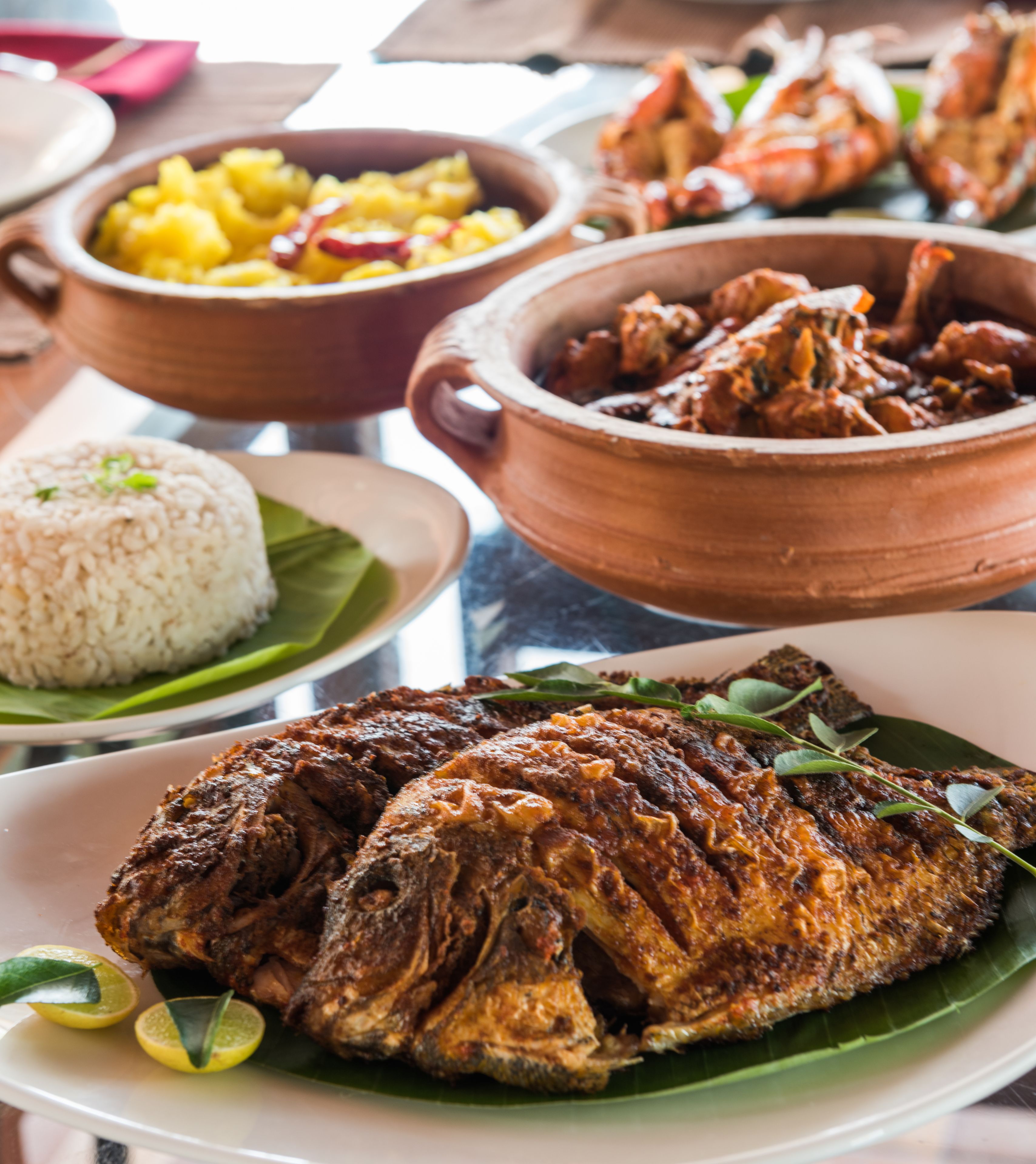 A variety of dishes including rice, fish, and seafood, served on traditional clay pots.
