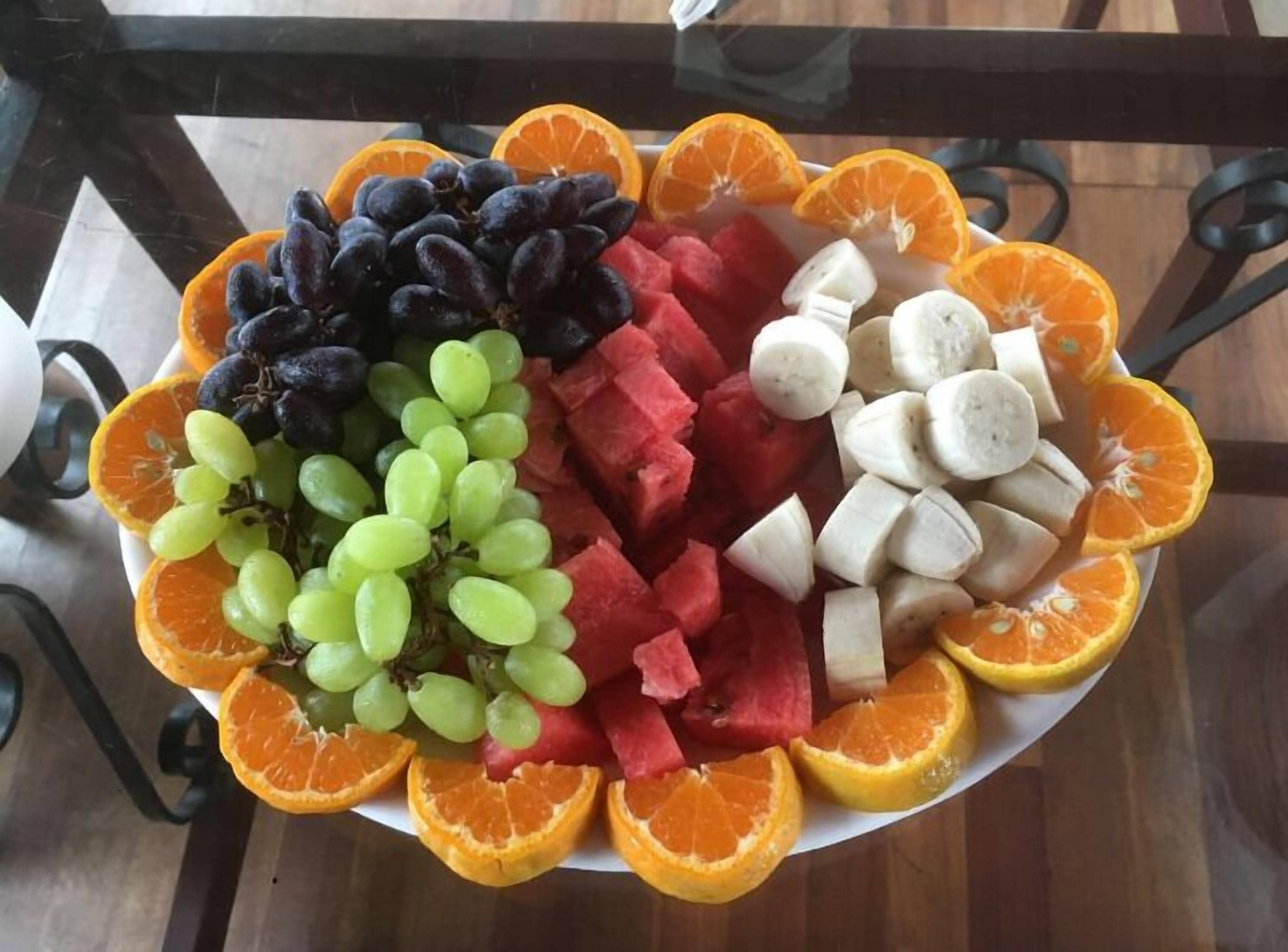 Una bandeja de frutas con uvas, sandía, plátanos y naranjas.