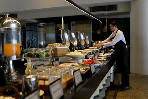 Montaje de bufé con distintos alimentos y un camarero atendiendo.