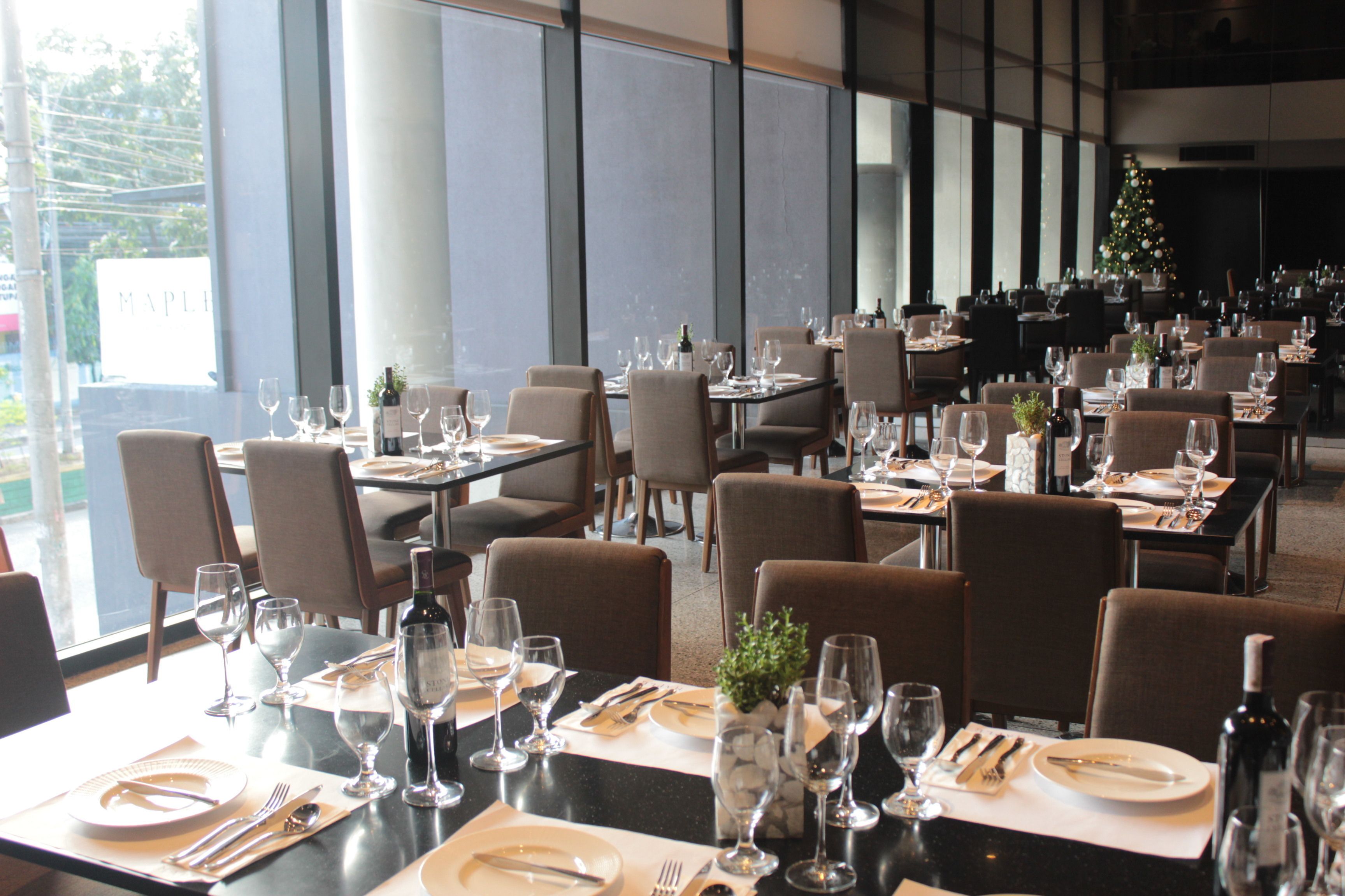 A restaurant with tables set for dining, featuring a modern interior and large windows.