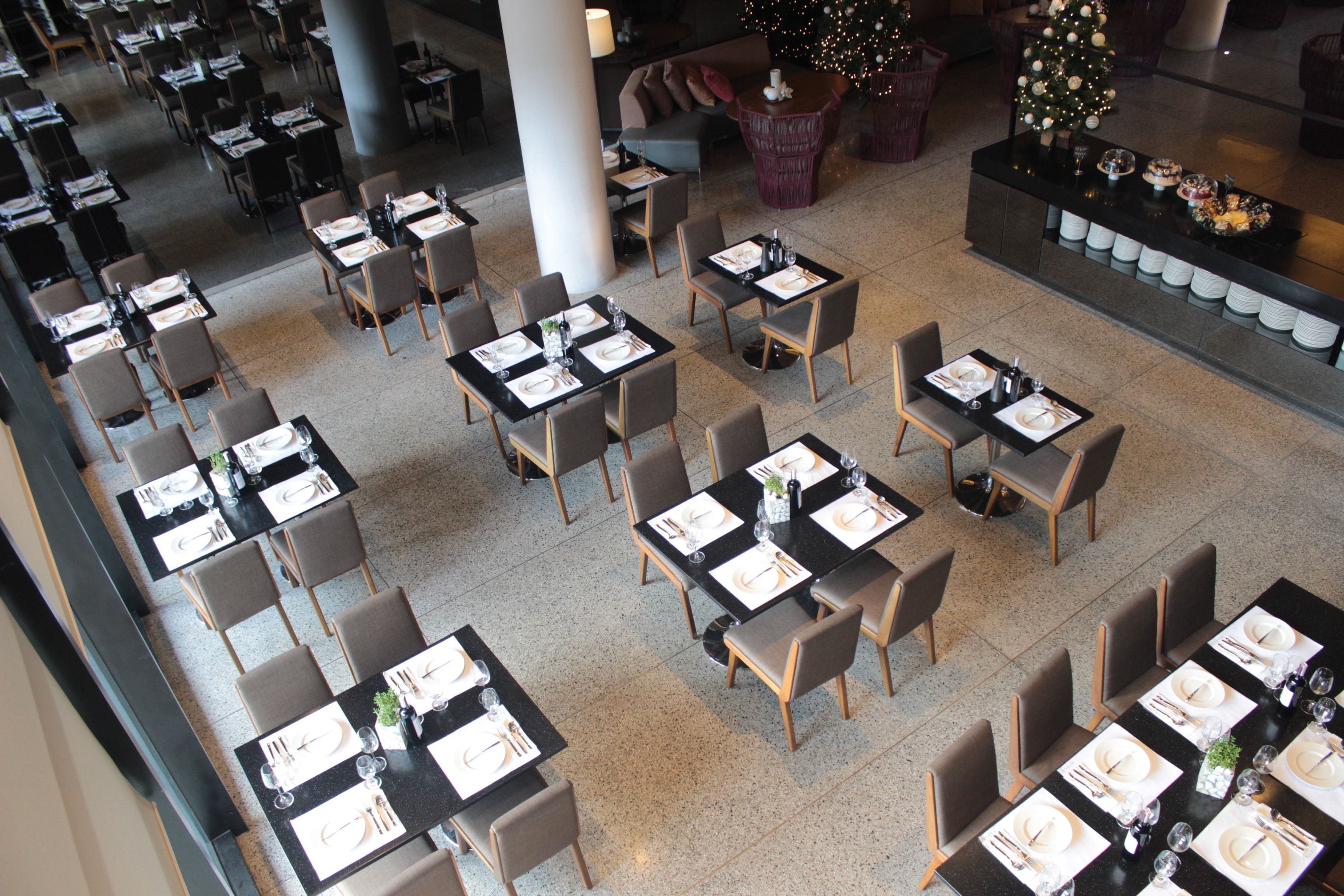 A spacious dining area with multiple tables set for service, a Christmas tree, and a seating area with couches.