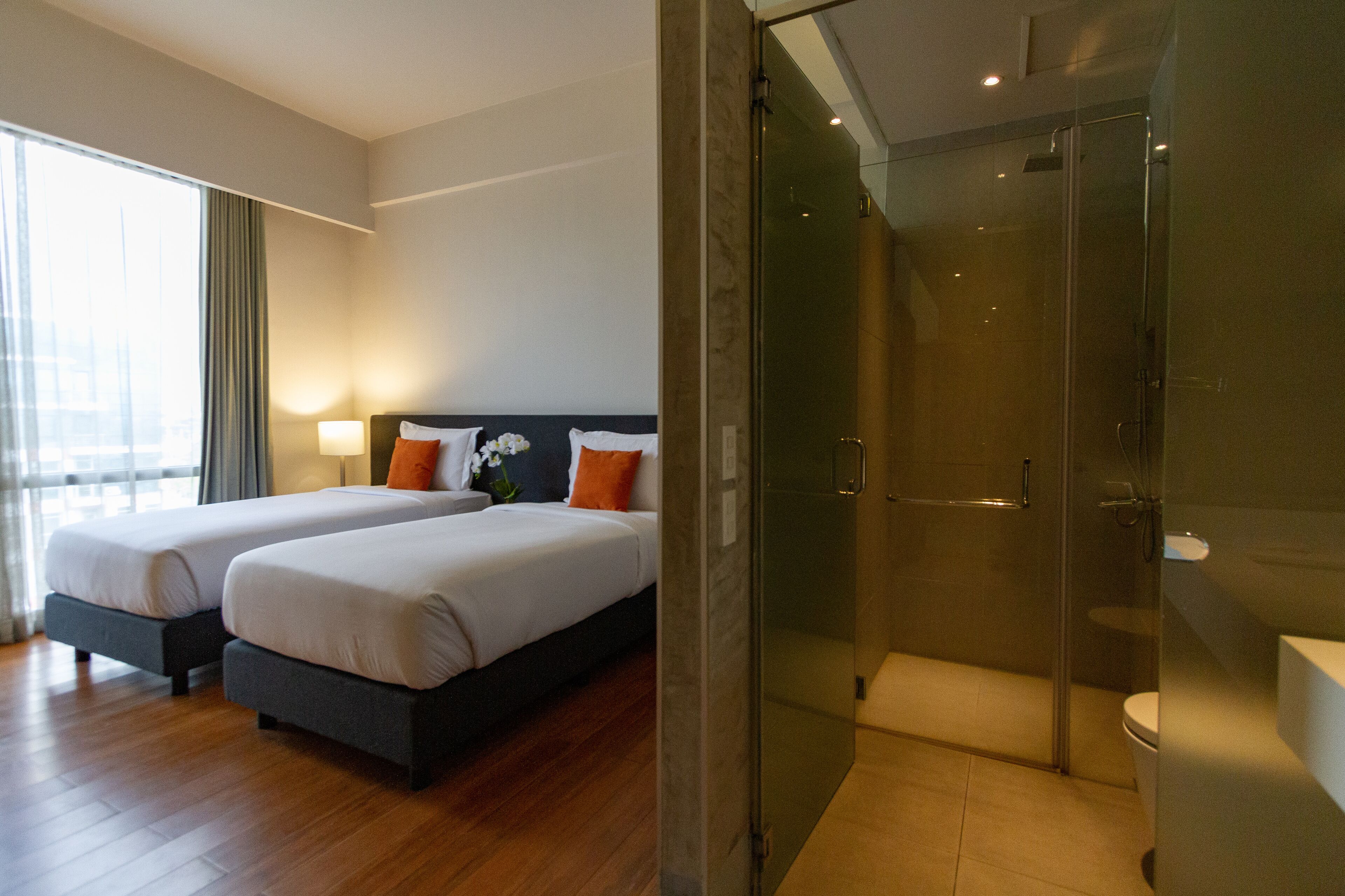 Ein Hotelzimmer mit zwei Betten, einer Duschkabine und Blick auf die Stadt.