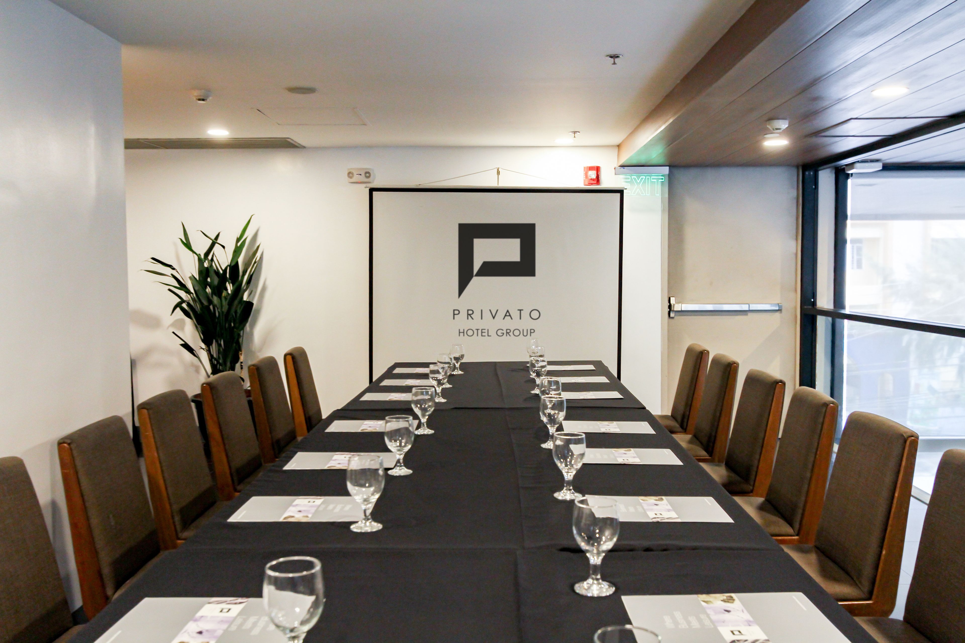 Une salle de conférence avec une longue table, des chaises et une enseigne indiquant « Privato Hotel Group ».