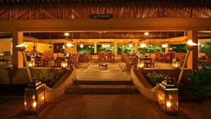An outdoor dining area with multiple tables and chairs, a central fire pit, and a sign reading "GATO KOLI". - Tuli Tiger Corridor (Kurai)