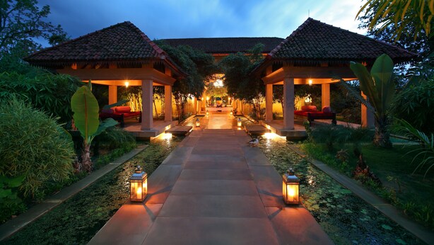 A pathway leading to a traditional-style building with a tiled roof, surrounded by lush greenery and illuminated by lanterns. - Tuli Tiger Corridor (Kurai)