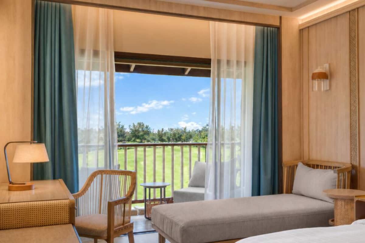 Een hotelkamer met balkon, een bed, een stoel, een tafel en een lamp.