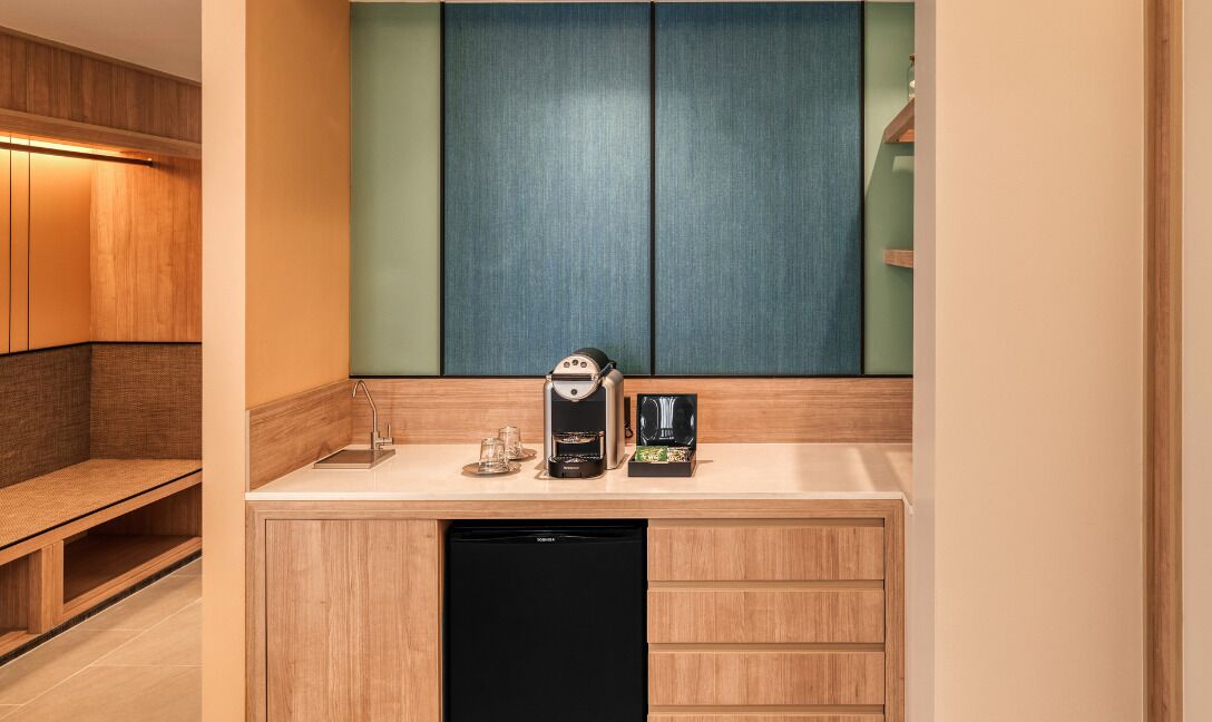 A compact kitchenette with a coffee maker, a small refrigerator, and a sink.