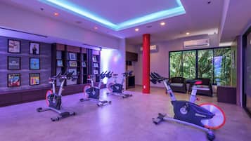 Ein modernes Fitnessstudio mit Ergometer, einer roten Säule und einer Wand mit gerahmten Bildern.