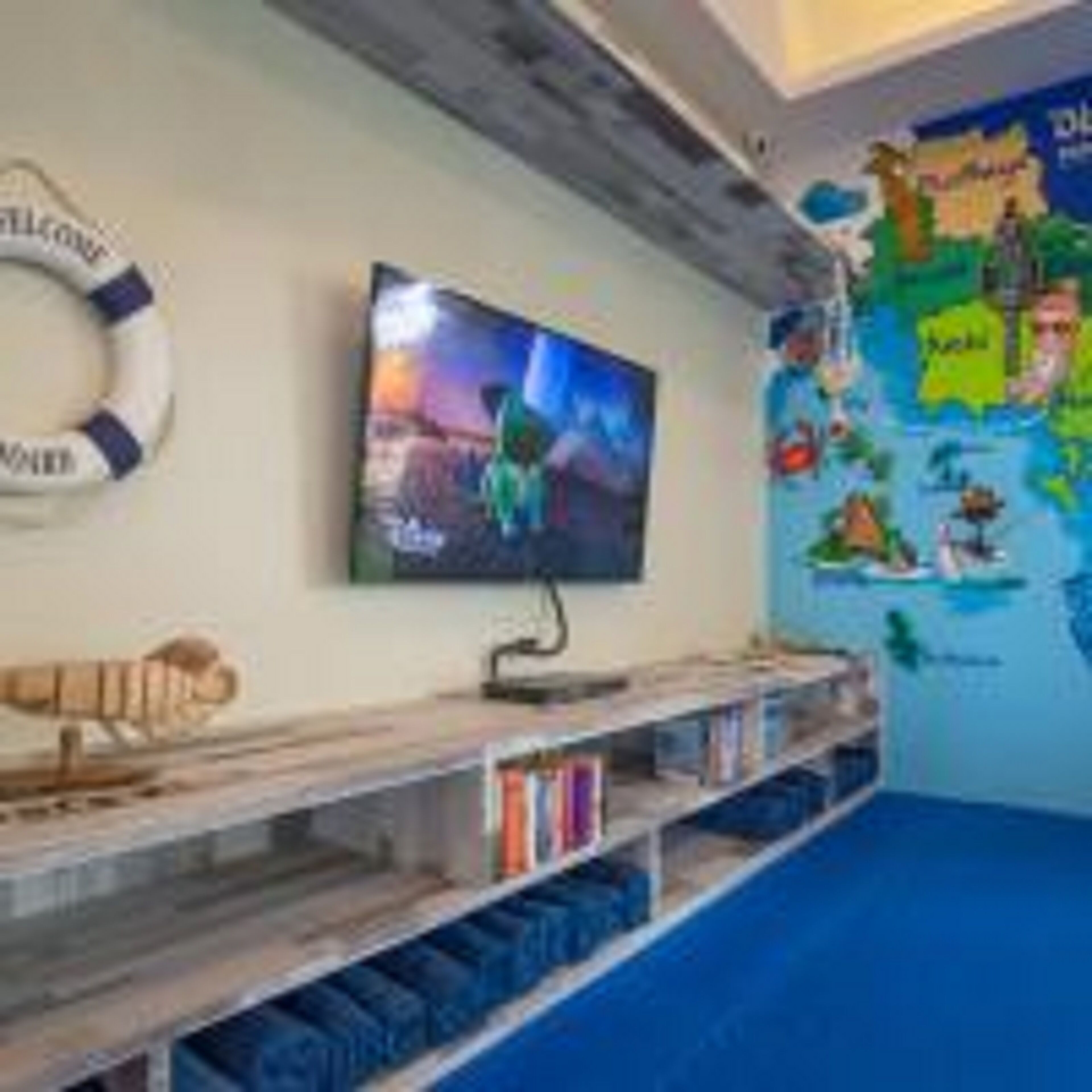 Una stanza con una televisione montata a parete, un salvagente appeso al muro e una mappa del mondo.