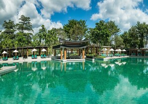 A large outdoor swimming pool with lounge chairs and umbrellas, surrounded by trees and a pavilion. - Dusit Thani Krabi Beach Resort (Krabi)