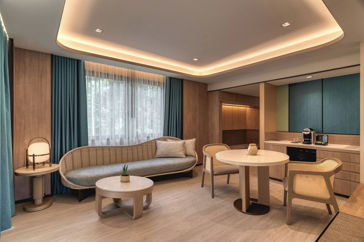 Una sala de estar moderna con un sofá, dos mesas redondas y un comedor.