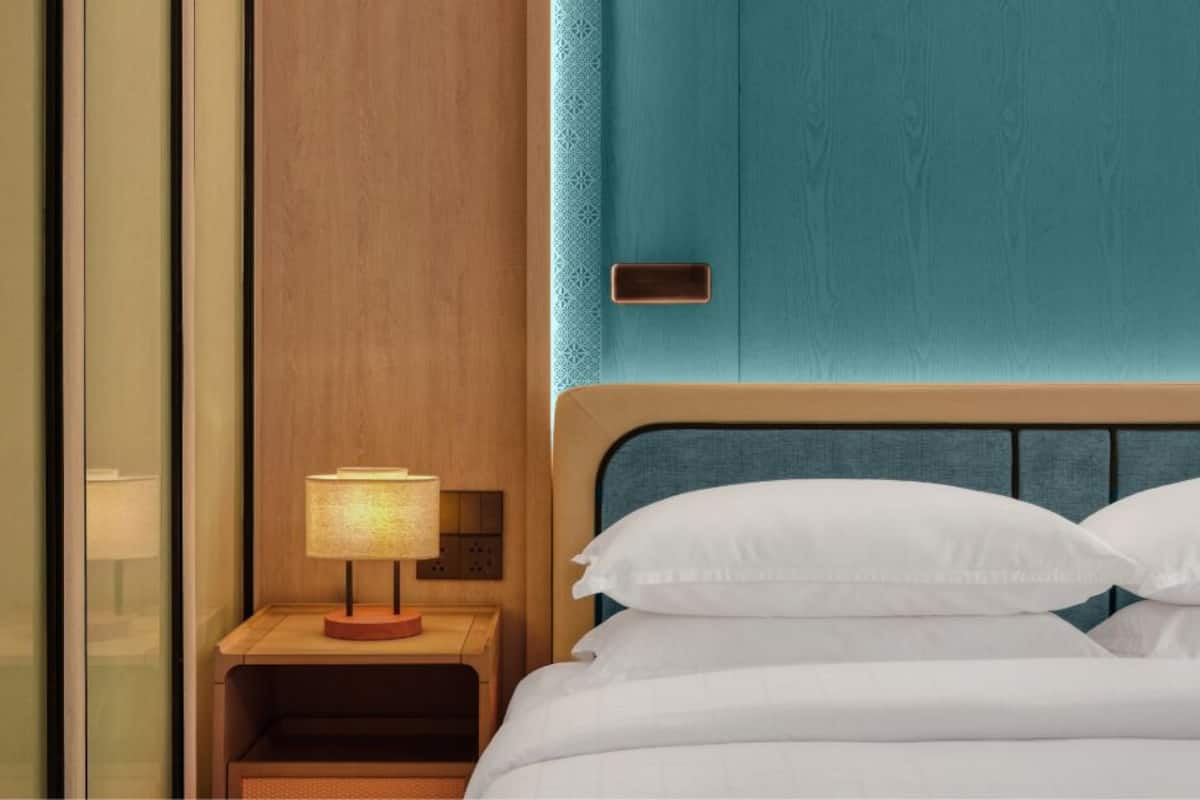 Een hotelkamer met een bed, een nachtkastje met een lamp en een houten wand.