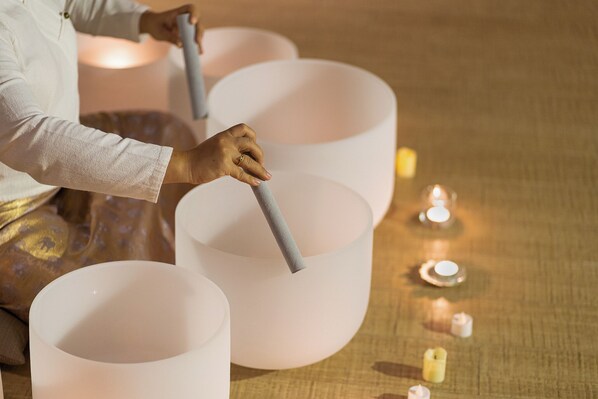 A person arranging large, white cylindrical objects on a textured surface with small candles nearby.