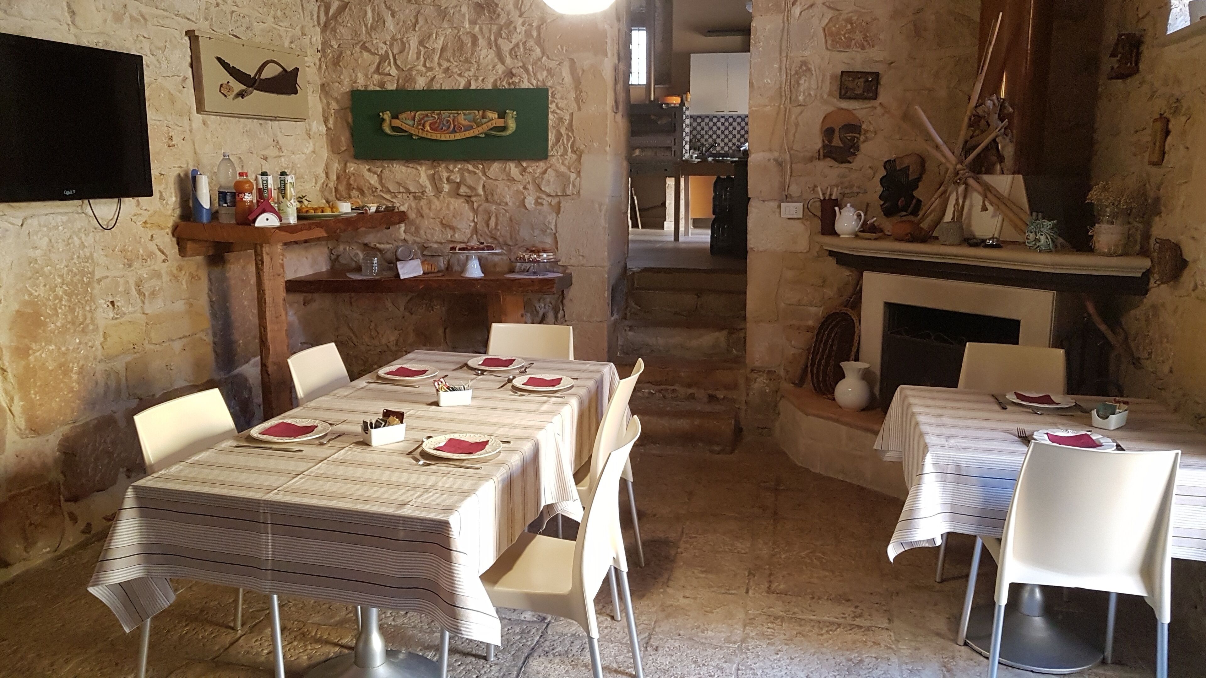 Un'area pranzo rustica con pareti in pietra, un camino e un televisore montato a parete.