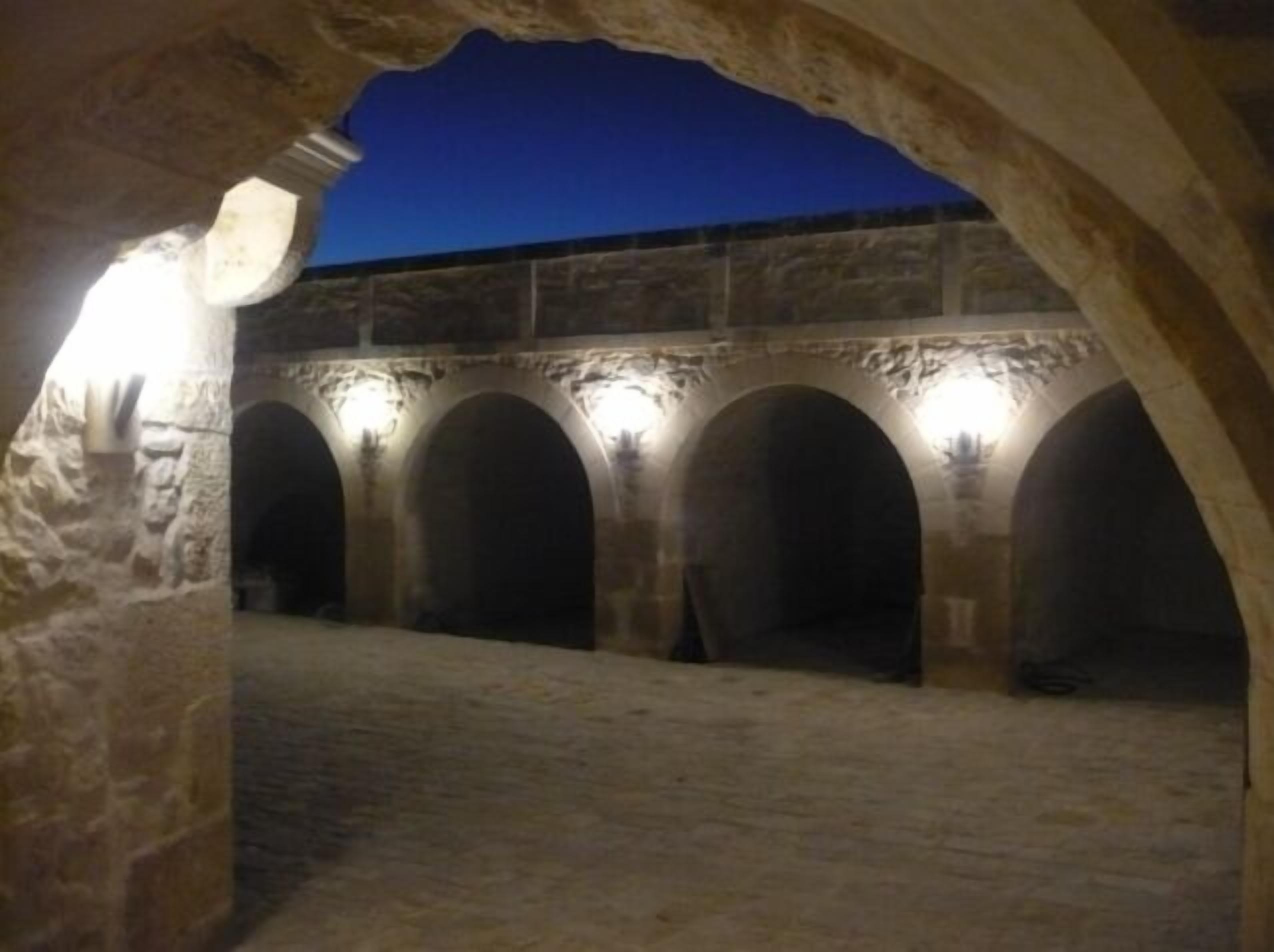 A series of stone arches in a dimly lit courtyard with a view of the night sky.