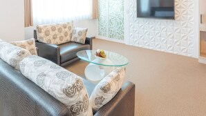 A modern living room with a sofa set, a glass coffee table, and a flat-screen TV mounted on a decorative wall. - Ful Won Hotel (Taichung)