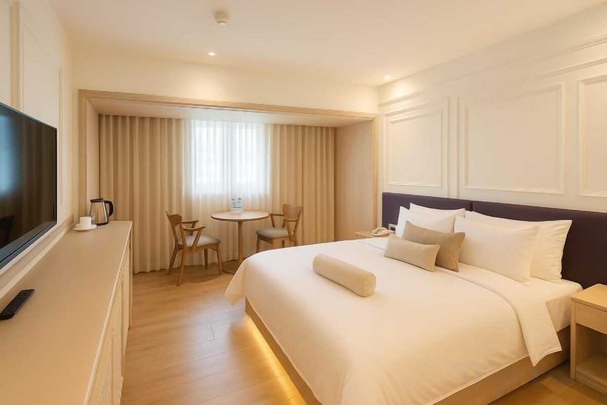 A hotel room with a bed, a TV, a desk, and a chair.