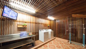 A laundry area with a flat-screen TV, washing machines, and a tiled floor. - Ful Won Hotel (Taichung)