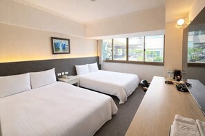 A hotel room with two beds, a desk, a chair, a nightstand, a phone, a picture frame, and a window with a view.